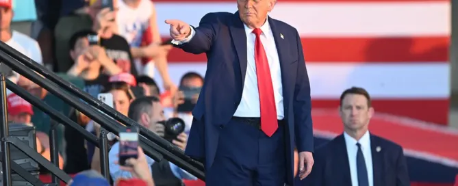 Donald Trump in a red USA hat pointing to the crowd at a 2026 America250 event.