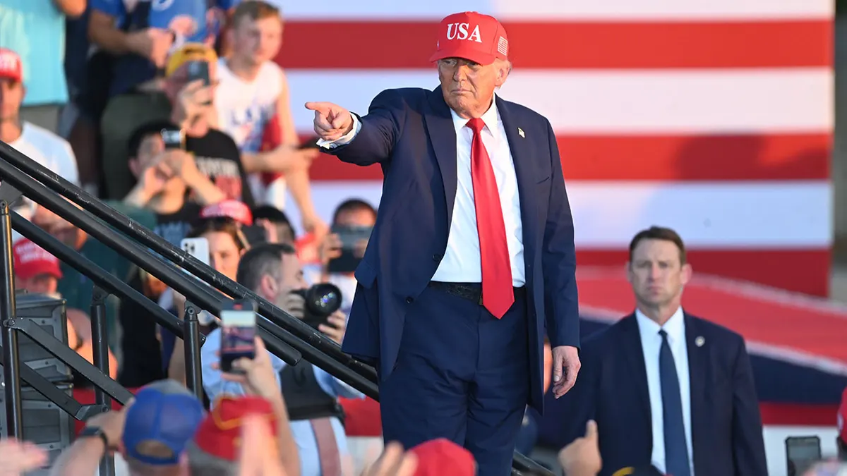 Donald Trump in a red USA hat pointing to the crowd at a 2026 America250 event.