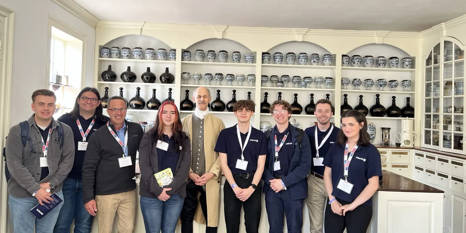 Zac Northup with students and a costumed historical interpreter in a historic apothecary.